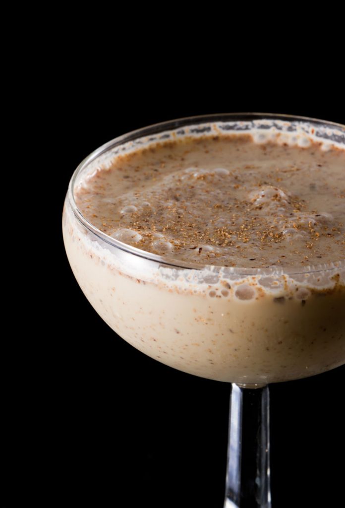 A close-up of a delicious Brandy Alexander Cocktail in a sidecar cocktail glass garnished with spiced sugar.
